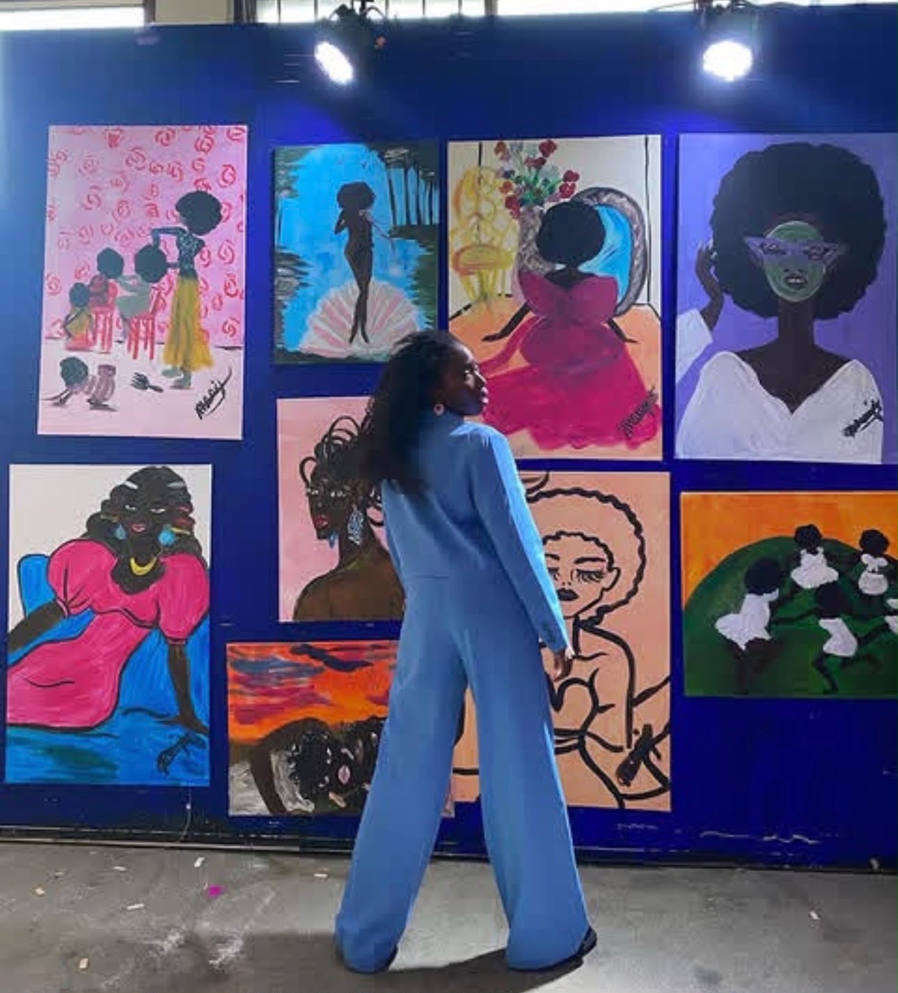 Michelle Amo in front of the exhibition wall of paintings
