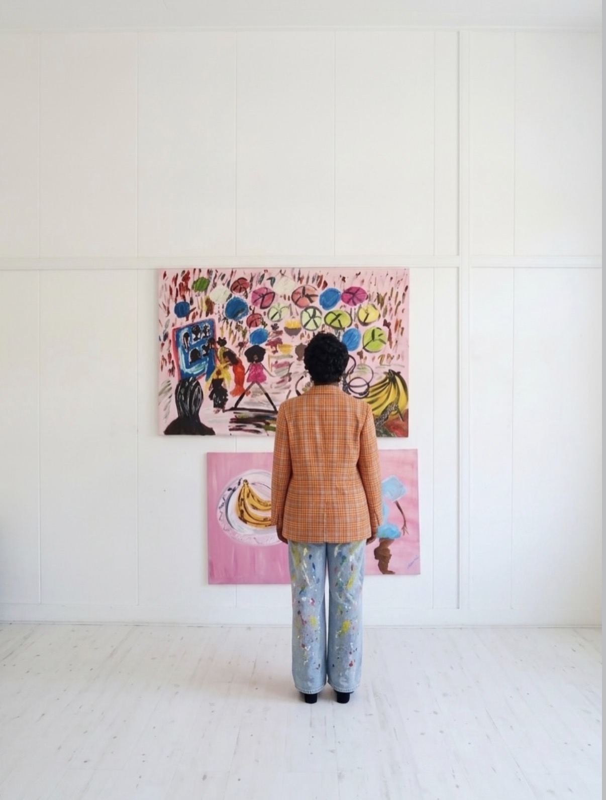 Michelle Amo standing among her paintings in the gallery